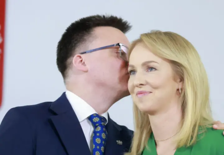 Szymon Hołownia szepcze coś do ucha swojej żonie Urszuli Brzezińskiej.