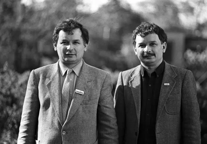 Dwóch mężczyzn w garniturach, jeden z przypinką "Solidarność".