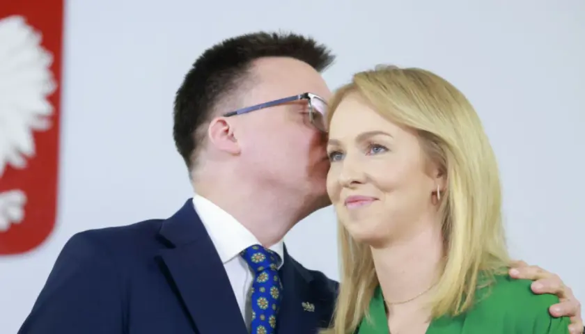 Szymon Hołownia szepcze coś do ucha swojej żonie Urszuli Brzezińskiej.
