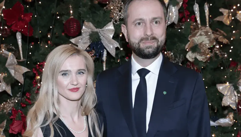 Para z uśmiechem na tle choinki.